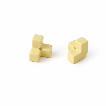 Two yellow acrylic puzzle bead pieces shown separately with their threading holes.