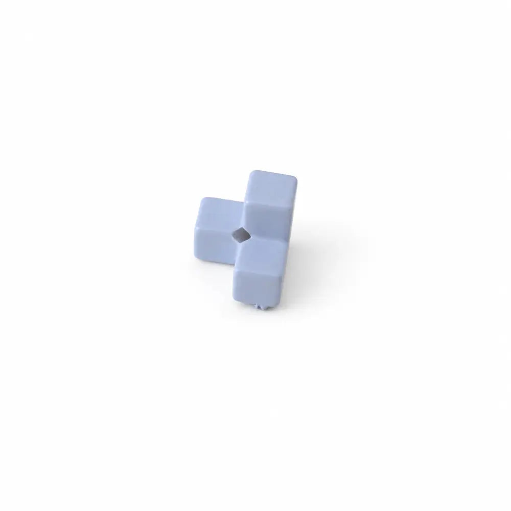 Close-up of a pale blue acrylic puzzle bead piece showing its stepped shape and threading hole.