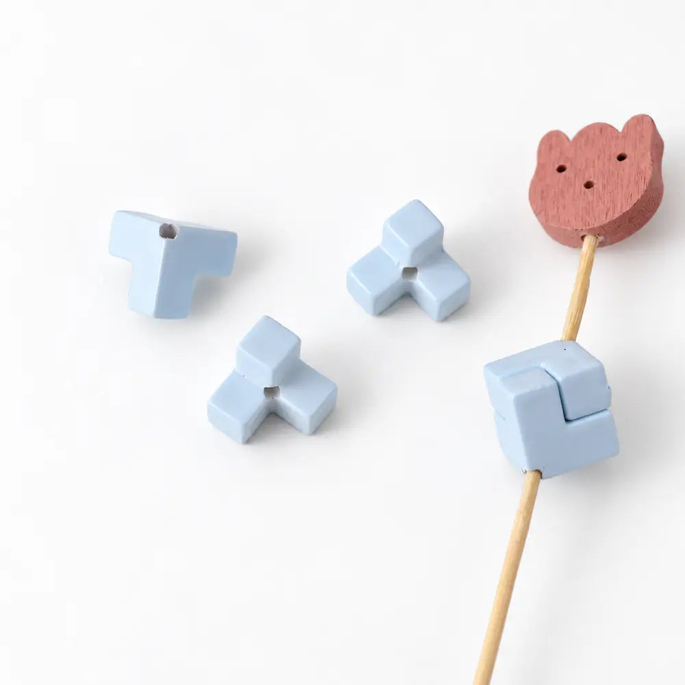 Sky blue acrylic puzzle pieces with visible threading holes and an assembled square on a display rod.