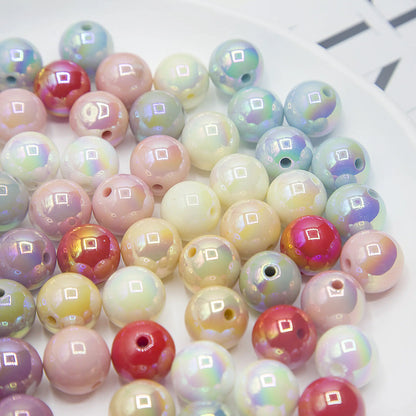 Mixed-color acrylic round beads with a glossy iridescent finish and visible holes on a white plate.