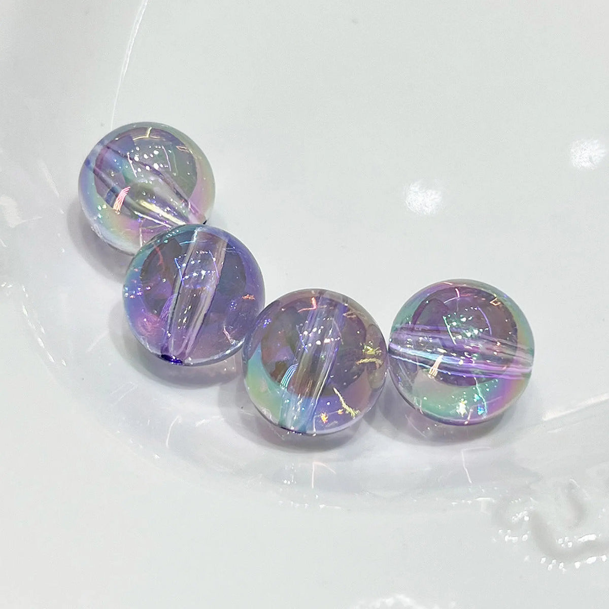 Four transparent purple acrylic round beads with iridescent reflections and visible through-holes.