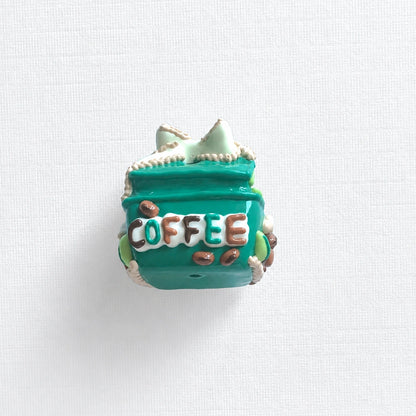 Back view of the teal gift-box bead with raised COFFEE lettering and brown bean-shaped details.