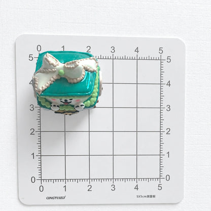 Top view of the puppy gift-box bead on a centimeter grid for approximate size reference.