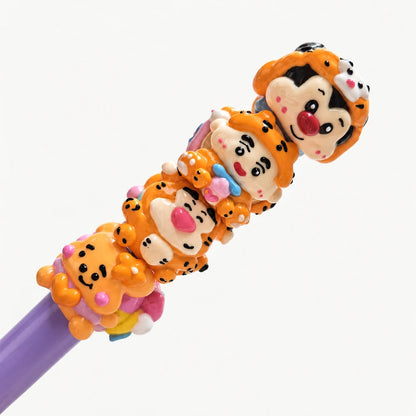 Four hand-painted acrylic beads with orange face designs arranged on a purple display rod.