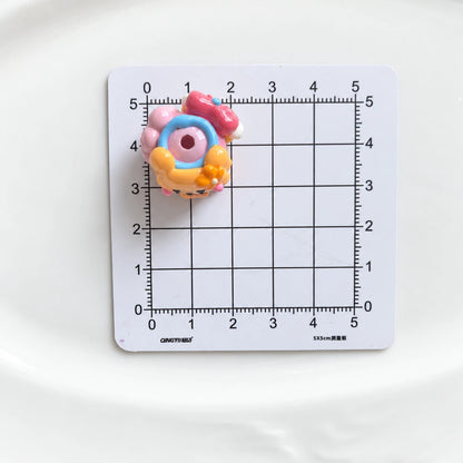 Top view of one decorated acrylic bead showing the threading hole on a centimeter grid for size reference.