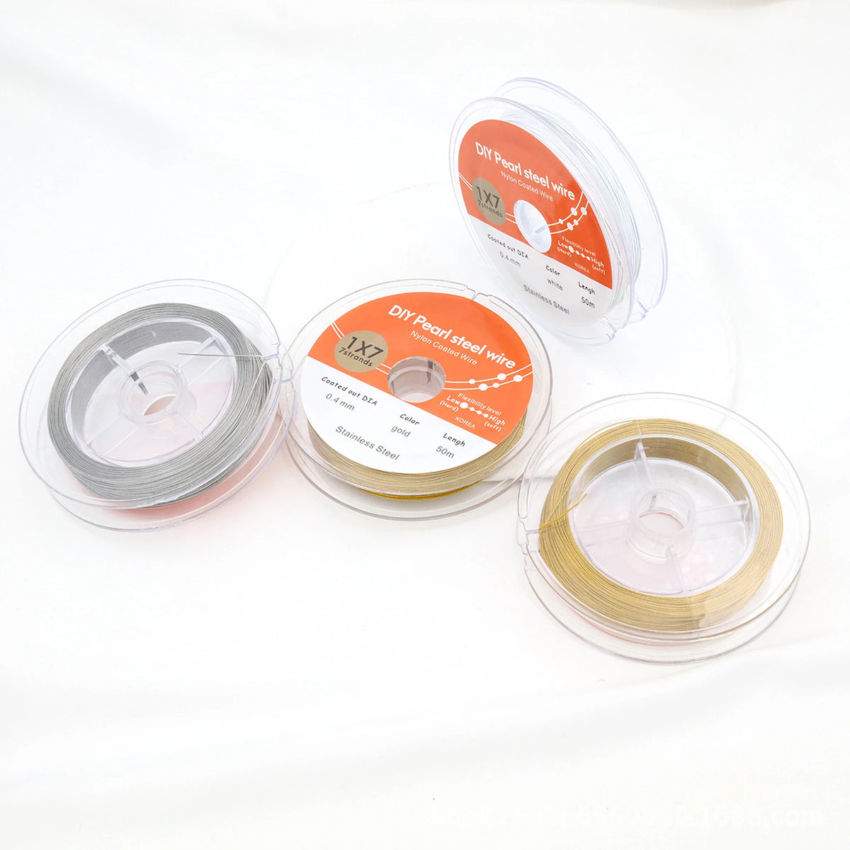 Overhead view of white, gold-tone and steel-colored beading wire spools showing their packaging.