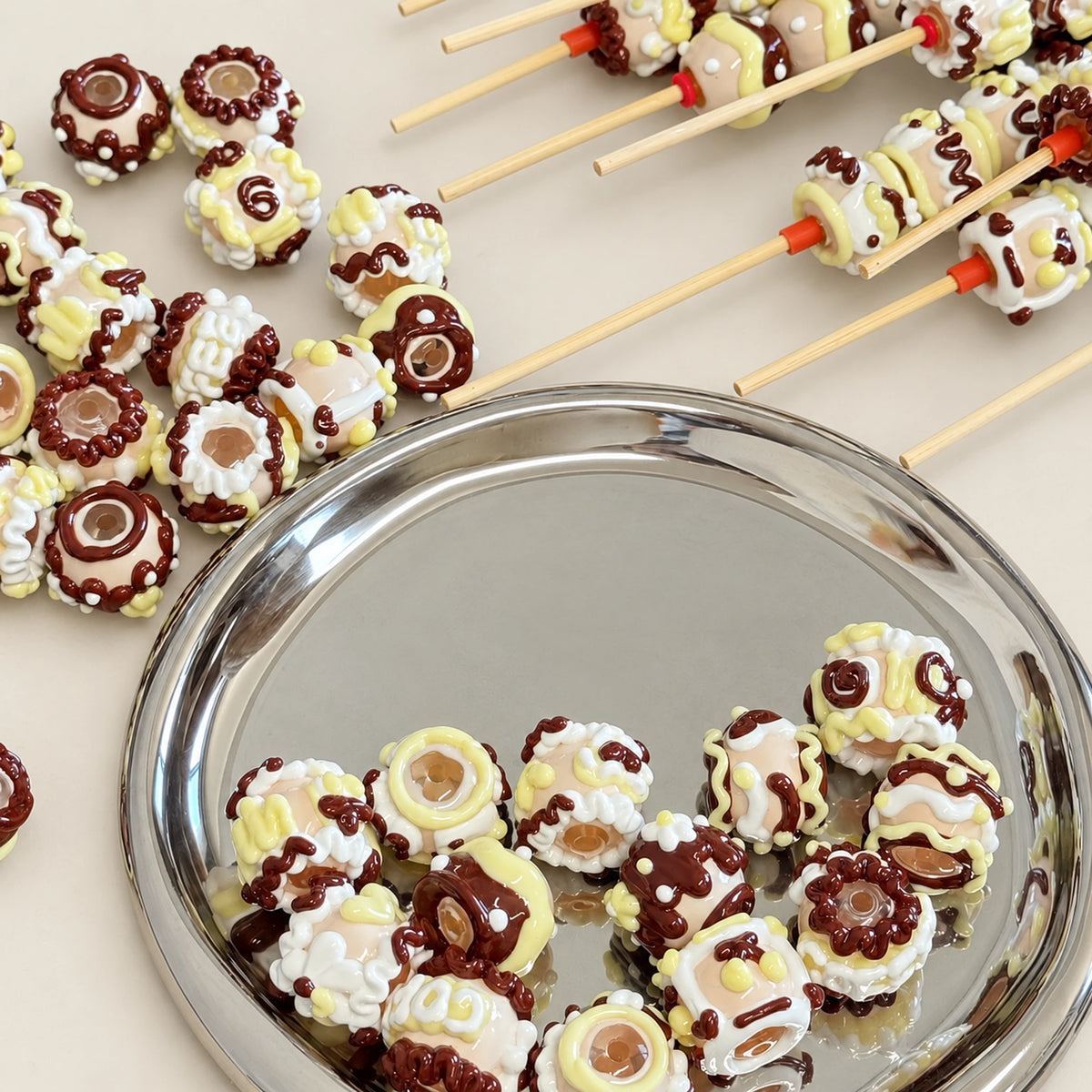 Close-up of hand painted chocolate colored beads showing swirled brown cream and pale yellow raised details and bead holes