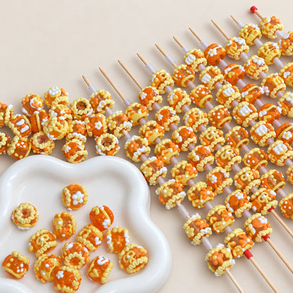 Jelly orange and yellow hand-painted beads with glossy raised flower and ribbon motifs on beadable display rods