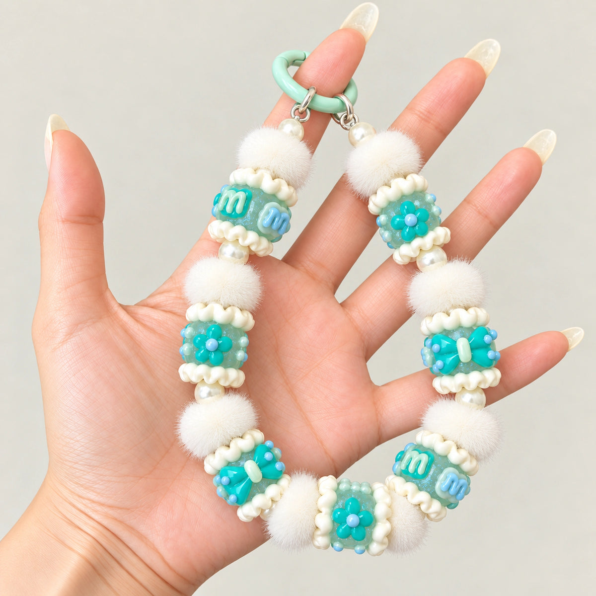 Example phone charm featuring luminous mint 3D handmade beads, white pom poms and pearl spacers; accessories not included