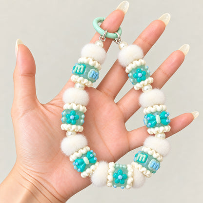 Example phone charm featuring luminous mint 3D handmade beads, white pom poms and pearl spacers; accessories not included