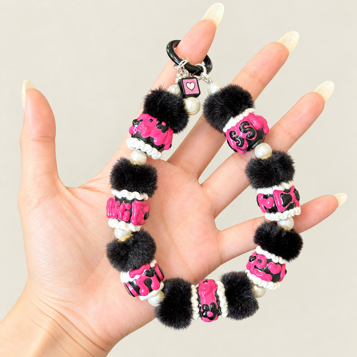 Handmade phone charm featuring midnight fuchsia painted beads black pom poms and pearl accents
