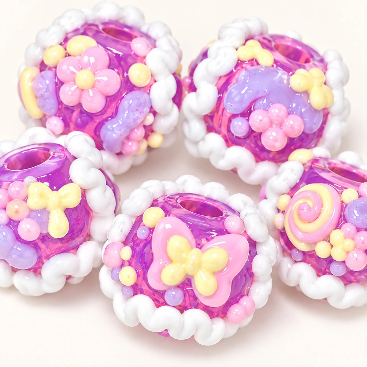 Five handmade taro grape purple beads showing flowers bows swirl designs and white piped trim