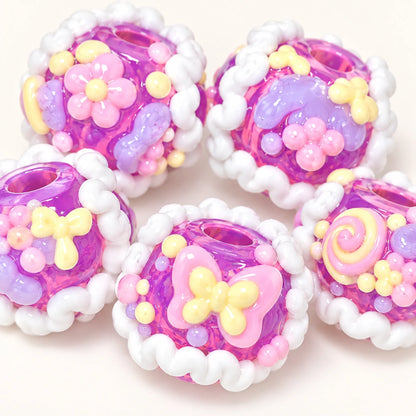 Five handmade taro grape purple beads showing flowers bows swirl designs and white piped trim